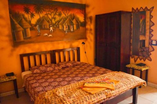a bedroom with a bed and a painting on the wall at Hotel Casa Sinkinling Gambia in Sere Kunda