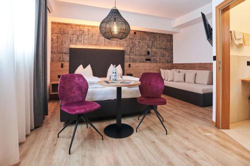 a hotel room with a table and two purple chairs at Pension Sunnhofer in Vilpiano