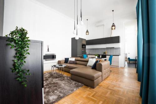 ein Wohnzimmer und eine Küche mit einem Sofa und einem Tisch in der Unterkunft Deluxe Quentin Home next to the Fashion Street in Budapest