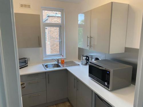 a kitchen with a sink and a microwave on a counter at Modern Central Apartment with Free Parking in Southampton