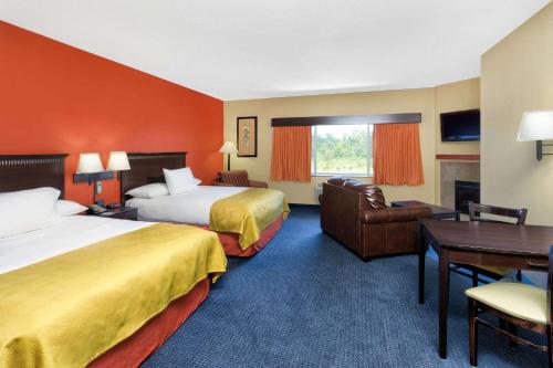a hotel room with two beds and a desk at AmericInn by Wyndham Vidalia in Vidalia