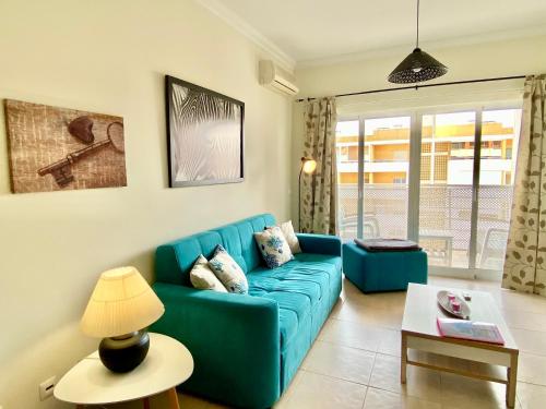 a living room with a blue couch and a table at Apartamento T1 Flamingo - Portimão - 1,5 km da Praia in Portimão