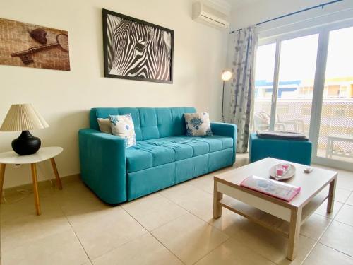 sala de estar con sofá azul y mesa en Apartamento T1 Flamingo - Portimão - 1,5 km da Praia en Portimão