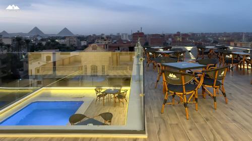 uma varanda com uma piscina e mesas e cadeiras em Sofia Pyramids Hotel no Cairo