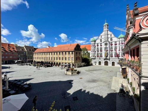 a large courtyard with a building with a clock tower at Marktplatz Memmingen in Memmingen