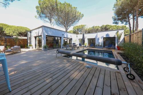 une arrière-cour avec une piscine et une terrasse en bois dans l'établissement Contemporary house with heated pool in a magnificent pine forest, à Aigues-Mortes