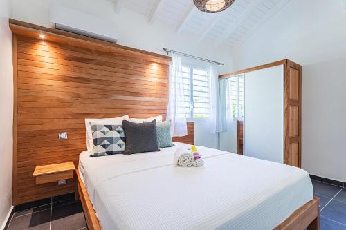 a bedroom with a large bed with a wooden headboard at Villa Plumbago in Sainte-Anne