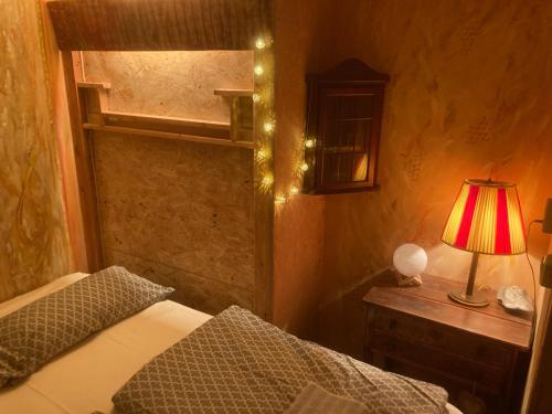 1 dormitorio con cama y mesita de noche con lámpara en Bungalow Biberspur, en Zieko