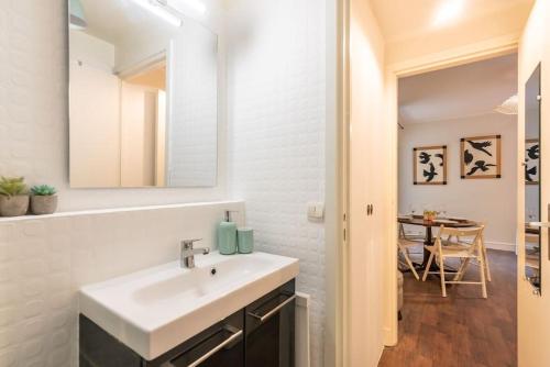 La salle de bains blanche est pourvue d'un lavabo et d'une table. dans l'établissement Appartement proche Champs Elysées, à Paris