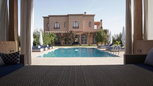 a view of a swimming pool with a building at Saphir Paon - Luxury Villa in the middle of a farm in Dar Achachir