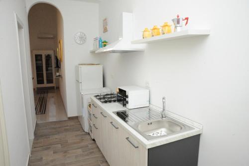 a white kitchen with a sink and a refrigerator at Massimino in Palermo
