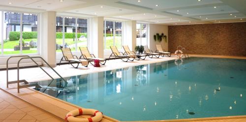 une piscine dans un hôtel avec des chaises et une personne y assise dans l'établissement Ferienwohnungen - Seehaus Riessersee, à Garmisch-Partenkirchen