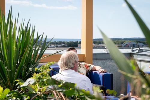 a woman with a suitcase sitting on a balcony at ProfilHotels Halmstad Plaza in Halmstad