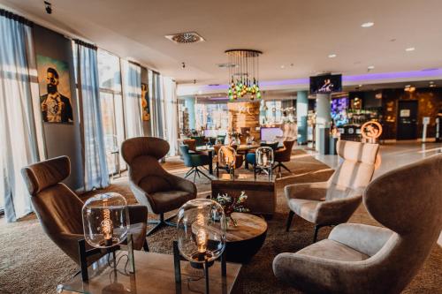 un salon avec des chaises et des tables dans une pièce dans l'établissement Mercure Hotel Hamburg City, à Hambourg