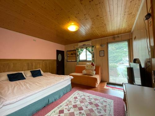 ein Schlafzimmer mit einem Bett und einem Sofa und einem Teddybär in der Unterkunft Linyuan Village in Jiufen