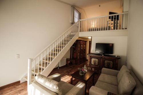a living room with a staircase with a couch and chairs at Riessersee Hotel in Garmisch-Partenkirchen