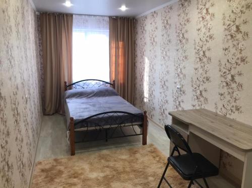 a bedroom with a bed and a desk and a window at Lux Home на Амурской in Ustʼ-Kamenogorsk