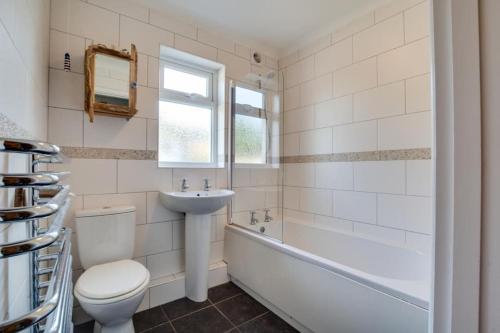 a bathroom with a toilet and a sink and a bath tub at Ebrel, Port Isaac Bay Holidays in Port Isaac
