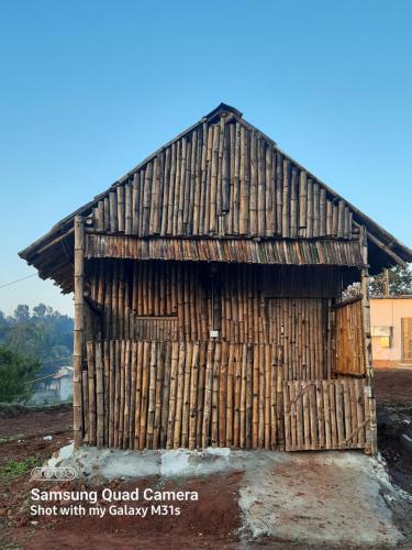 un pequeño edificio de madera sentado en la parte superior de un campo en Moongil Kudil en Yelagiri