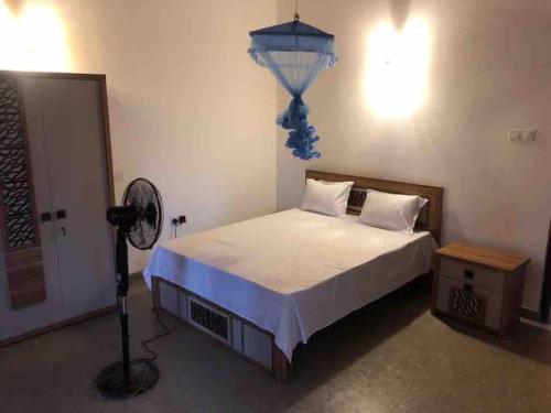 a bedroom with a bed with a fan and a lamp at SOHA Residency in Gampaha