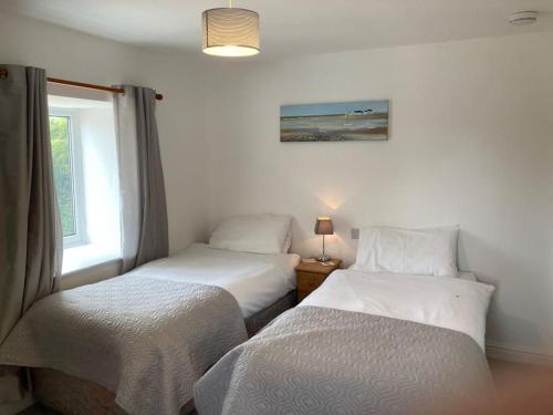two beds in a room with a window and a bedskirts at The Granary in Bridlington