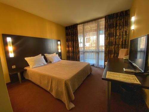 バンスコにあるMaraya Hotel Banskoのベッド、デスク、テレビが備わるホテルルームです。