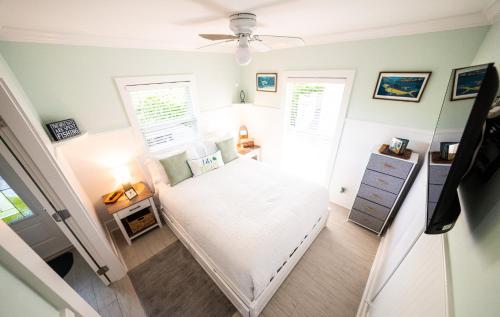 a small bedroom with a white bed and two windows at Key Lime Cottage in the heart of Islamorada in Islamorada