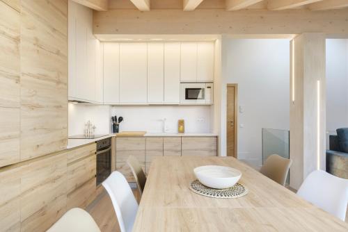 cocina y comedor con mesa de madera y sillas en Apartamentos La muralla de Jaca en Jaca