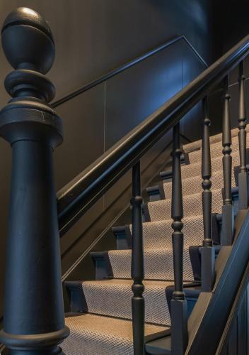 a spiral staircase with a black handrail and stairs at B&B De Oude Dorpsslagerij in Nuth
