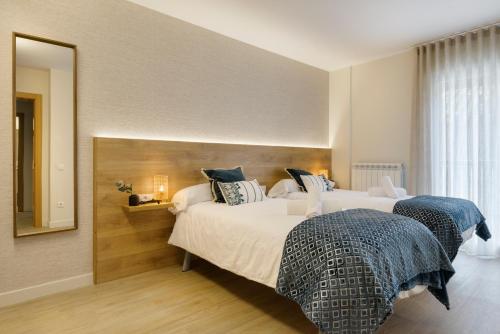 a hotel room with two beds and a mirror at Apartamentos La muralla de Jaca in Jaca