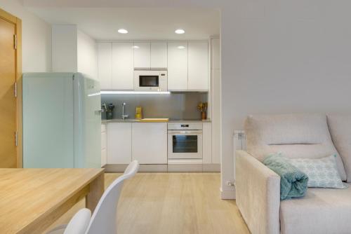 a kitchen with white cabinets and a chair and a table at Apartamentos La muralla de Jaca in Jaca