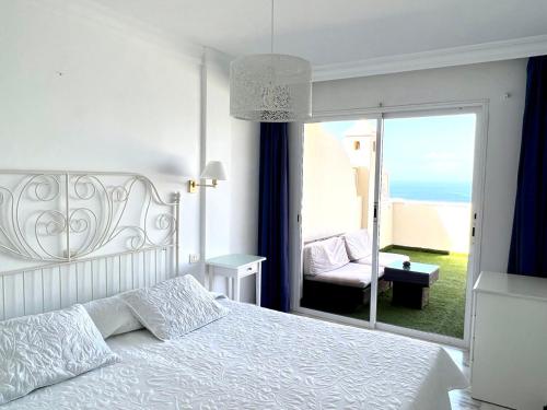 a bedroom with a white bed and a window with a chair at Buenavista Top Floor Penthouse in Santiago del Teide