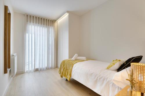 a white bedroom with a bed and a large window at Apartamentos La muralla de Jaca in Jaca