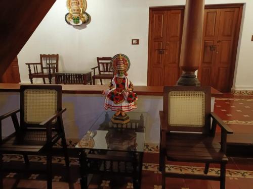OttappālamにあるKalappura Farm House Heritageの椅子2脚、時計付きテーブルが備わる客室です。