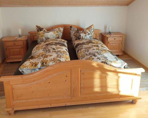 a bedroom with a wooden bed and two night stands at Gasthaus Schaupp in Kollnburg