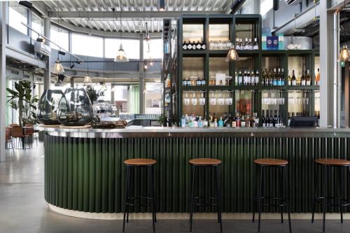 a green bar in a restaurant with stools at Basecamp Hotel Dortmund in Dortmund