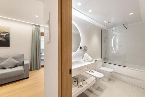 Odyssey Rooms Alicante في أليكانتي: حمام ابيض مع مرحاض واريكة