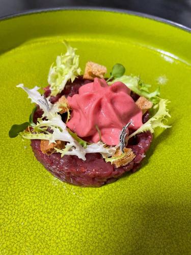 a green plate with a sandwich with lettuce and sauce at Innesti Rooms&Apartments - Le camere in Pergine Valsugana