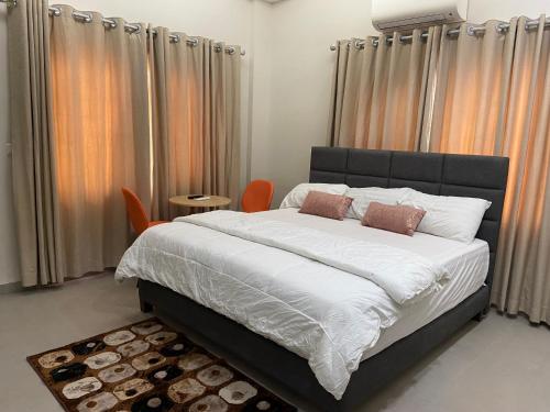 een slaapkamer met een groot bed en oranje stoelen bij Queens View Apartment in Accra