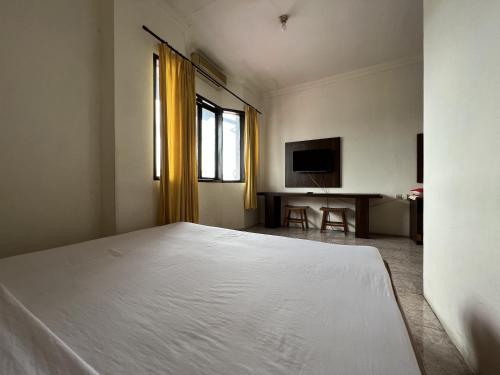 um quarto com uma cama branca e uma televisão em OYO 92098 Kost Orange Syariah em Gusung