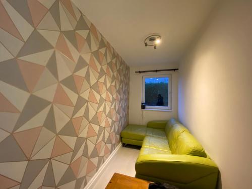 a living room with a green couch and a geometric wall at Louise street in Fife