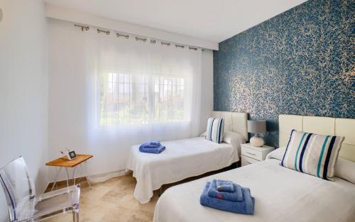 sypialnia z 2 łóżkami i niebieską ścianą w obiekcie Cozy Beach Side Apartment With Pool w mieście Estepona