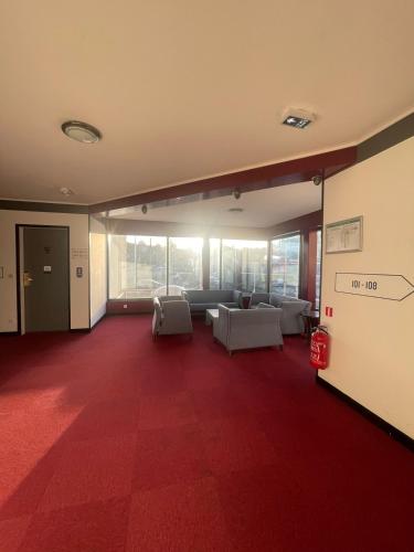 a large living room with a red carpeted floor at Kyriad Saint Fargeau Ponthierry - Apollonia in Saint-Fargeau-Ponthierry