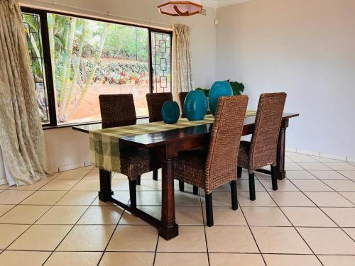 een eettafel met stoelen en blauwe vazen erop bij Ezrom Bright Holiday Home in Port Shepstone