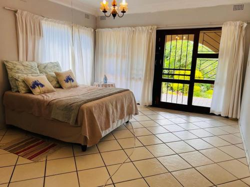 een slaapkamer met een bed en een groot raam bij Ezrom Bright Holiday Home in Port Shepstone