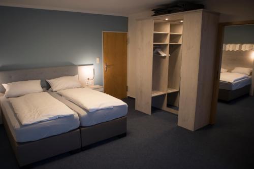 a small bedroom with two beds and a closet at Hotel Am Friesenstrand in Butjadingen