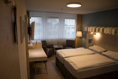 a small hotel room with two beds and a couch at Hotel Am Friesenstrand in Butjadingen