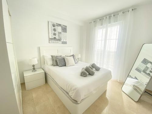 Dormitorio blanco con cama blanca y espejo en Small Oasis #2 - Manilva, en Estepona
