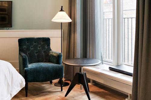 a bedroom with a chair and a table and a lamp at Hotel Kong Arthur in Copenhagen