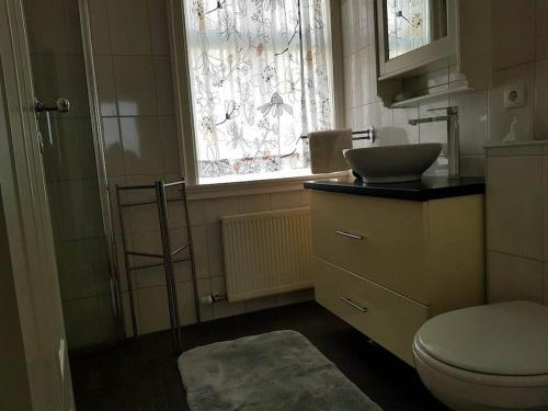 a bathroom with a toilet and a sink and a window at Tanginn in Stykkishólmur